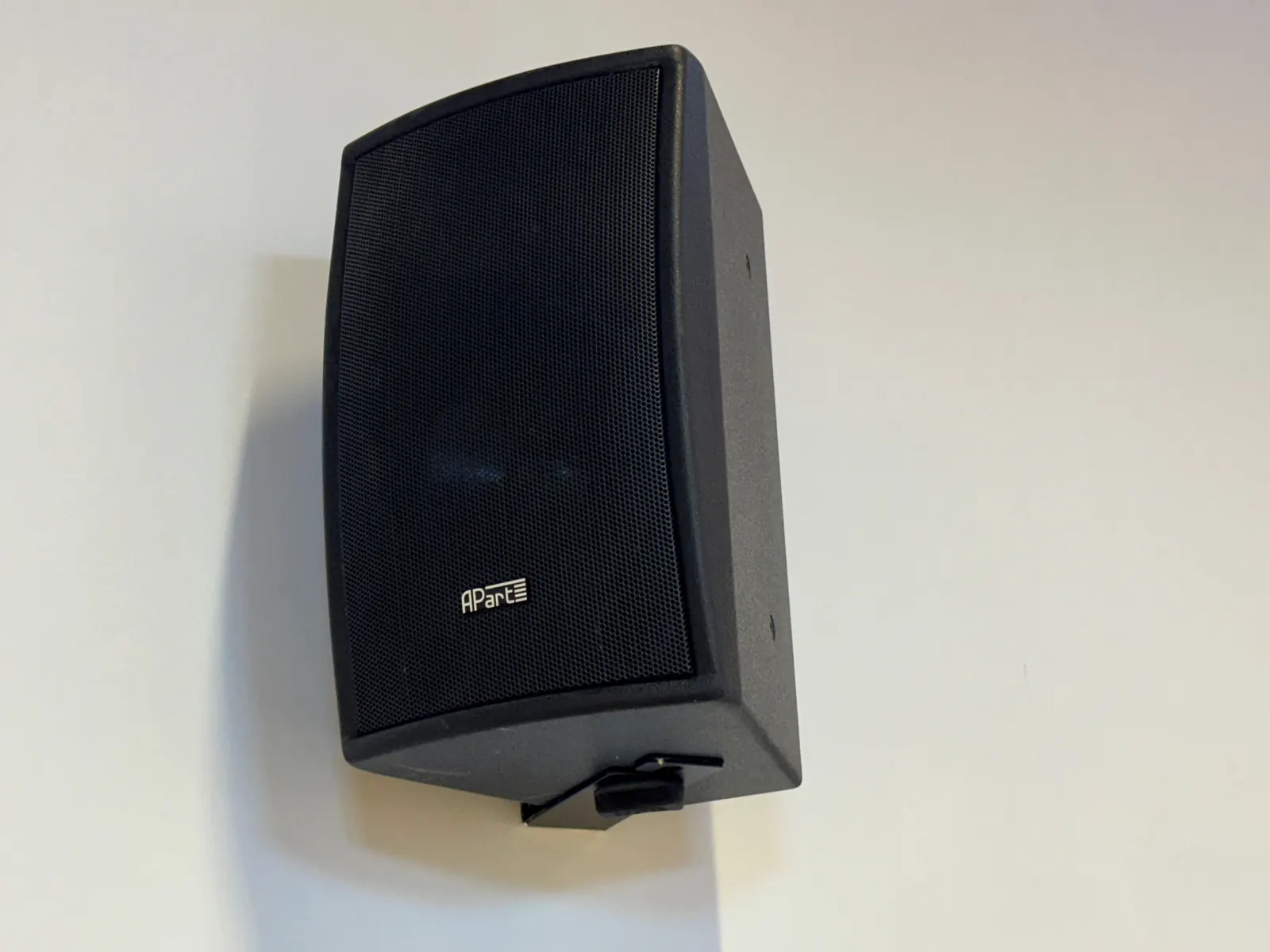 Enceinte noire fixée au mur de la grande salle.