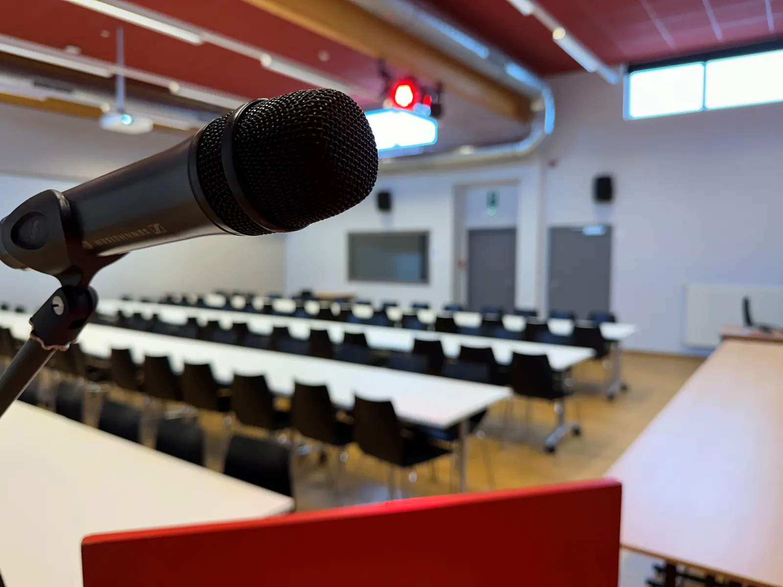 Micro sans fil sur son support, salle de conférence en arrière-plan.