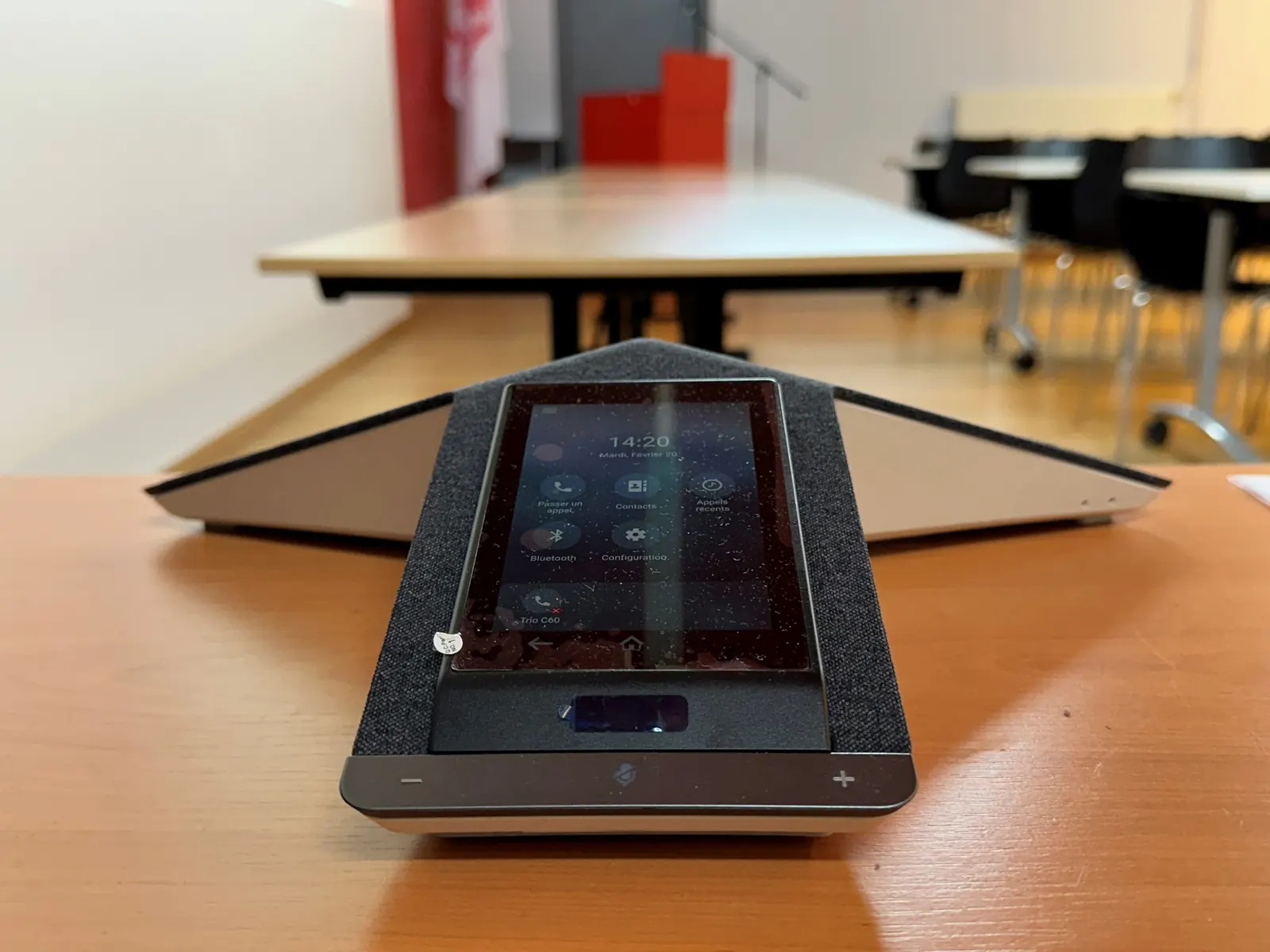 Téléphone de conférence à écran tactile posé sur une table.