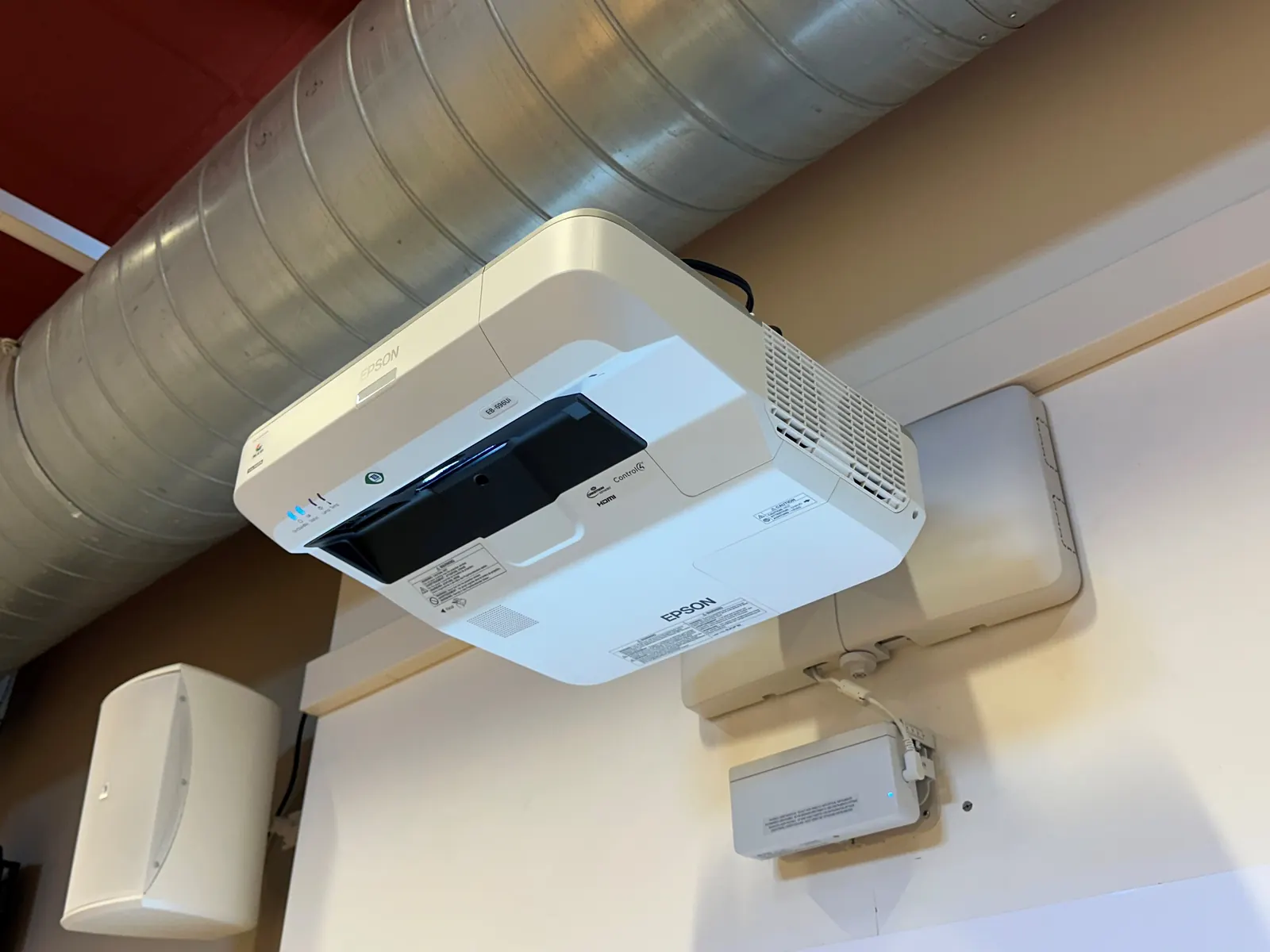 Vidéo-projecteur à courte focale fixé au-dessus de l'écran de la petite salle.